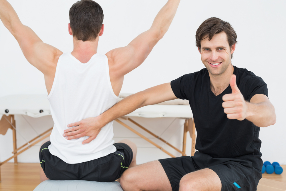 Two men exercising, one stretching and one with his thumb up